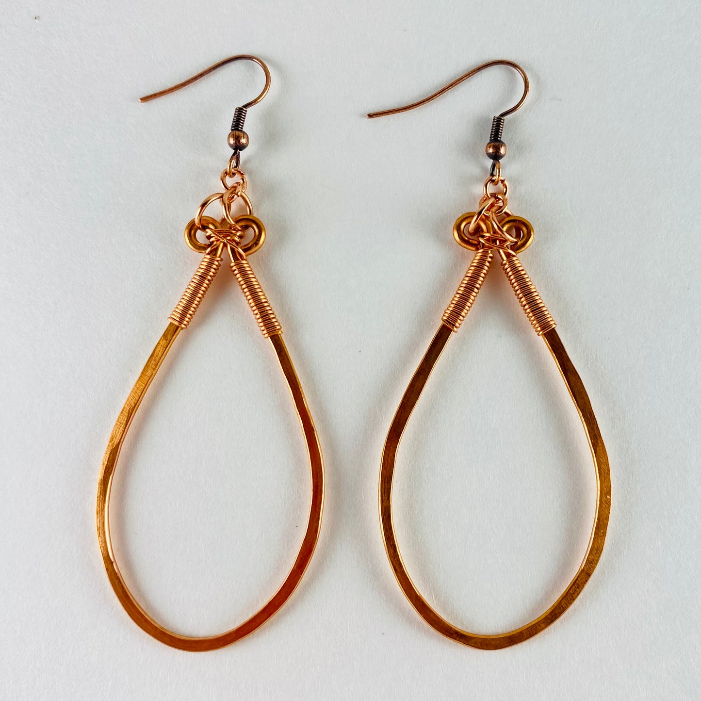 Dangling hammered copper teardrop shaped earrings wrapped with 20 gauge wire.