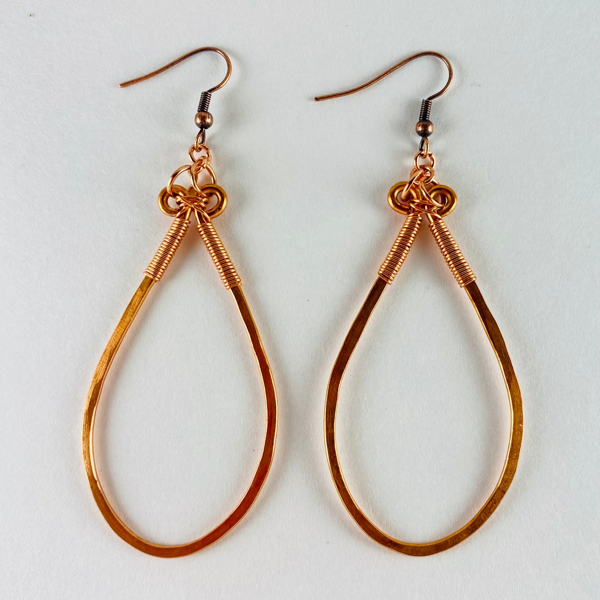 Dangling hammered copper teardrop shaped earrings wrapped with 20 gauge wire.