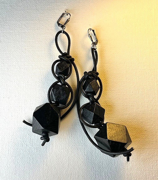 Black geometric earrings on a textured off-white background.